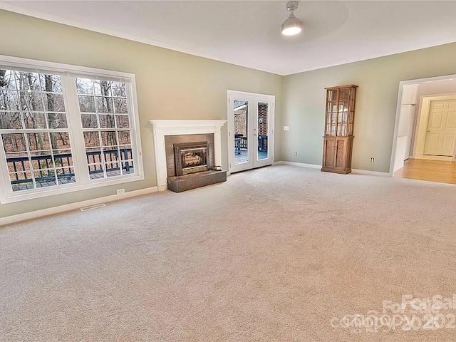 unfurnished living room with carpet flooring, a brick fireplace, french doors, baseboards, and visible vents