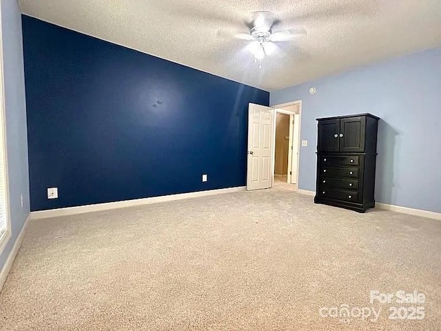 unfurnished bedroom featuring baseboards, a textured ceiling, and light carpet
