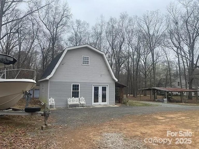 back of house with a gambrel roof and french doors