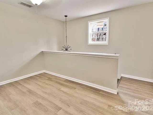 unfurnished room featuring baseboards, wood finished floors, and visible vents
