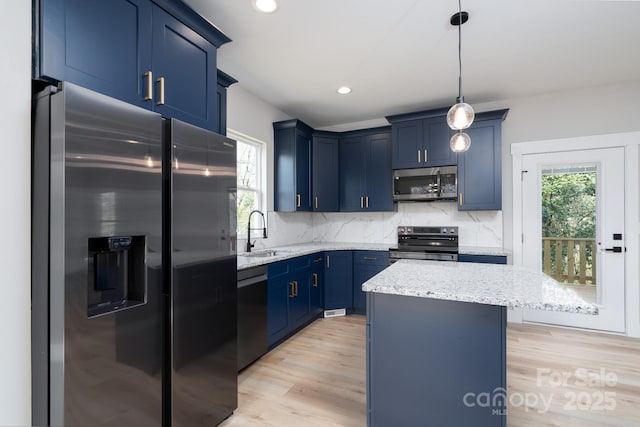 kitchen with light stone counters, blue cabinets, stainless steel appliances, a sink, and decorative backsplash