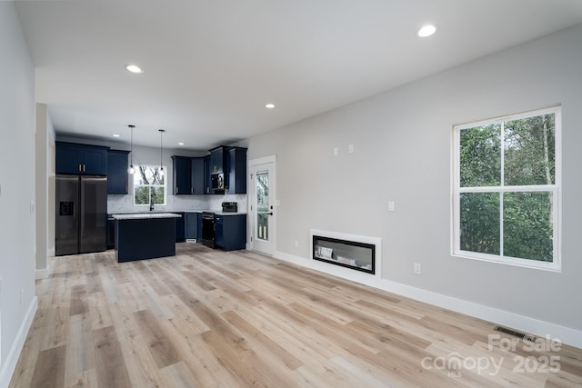 kitchen with built in fridge, visible vents, stainless steel microwave, stove, and blue cabinets