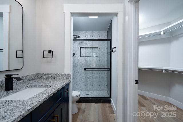 bathroom featuring vanity, wood finished floors, a shower stall, and toilet