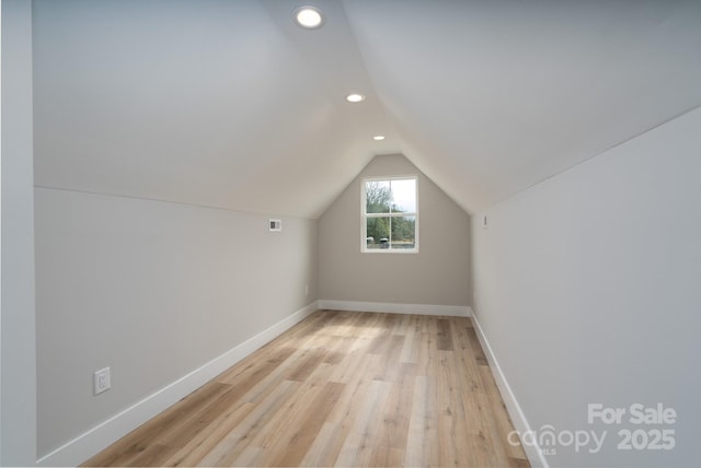 additional living space featuring light wood-type flooring, vaulted ceiling, baseboards, and recessed lighting