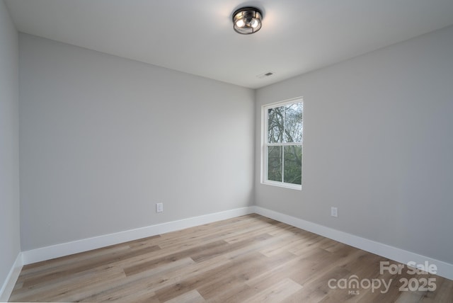 spare room with baseboards, visible vents, and light wood finished floors