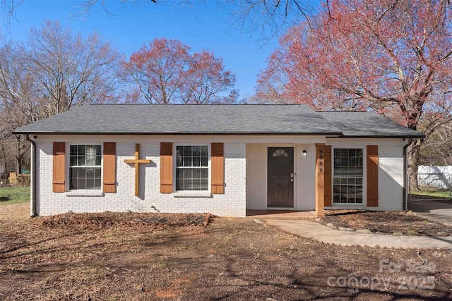 single story home with fence, brick siding, and roof with shingles