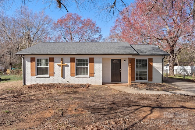 ranch-style house featuring brick siding, a shingled roof, and fence