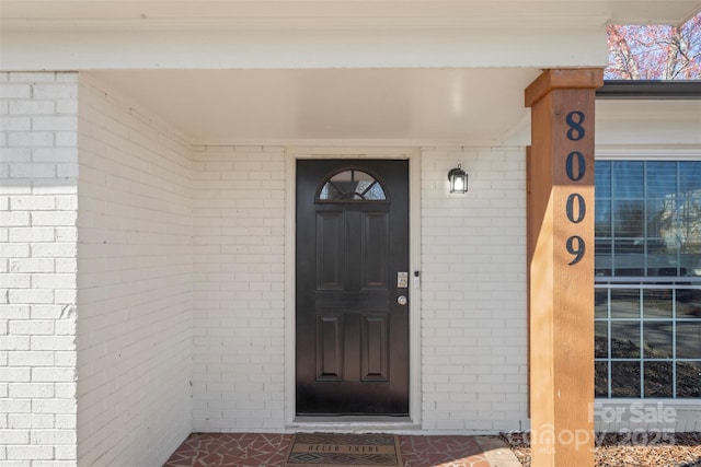 view of exterior entry featuring brick siding