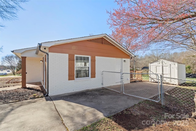 view of side of property with brick siding, a storage unit, an outdoor structure, and fence