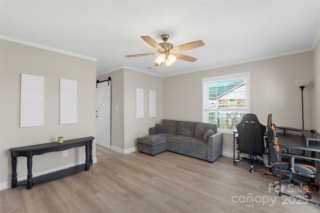 office area featuring a barn door, a ceiling fan, light wood-style flooring, and crown molding