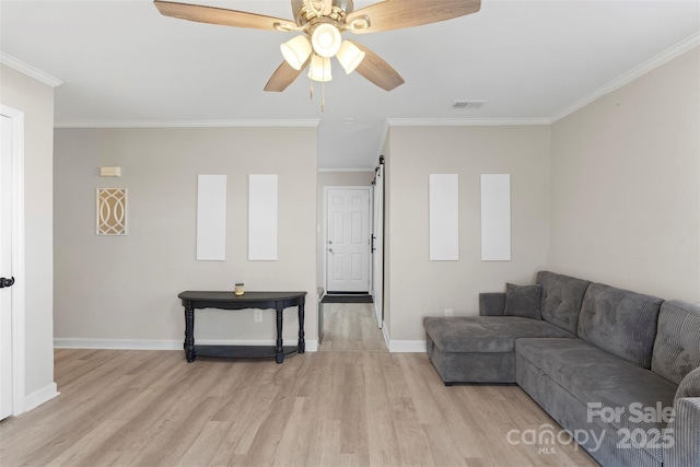 living room with a barn door, light wood-style floors, visible vents, and ornamental molding