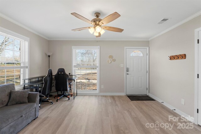 foyer entrance with a wealth of natural light, light wood finished floors, and ornamental molding