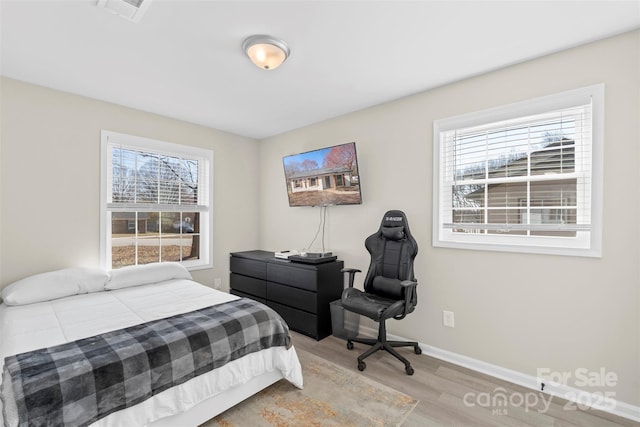 bedroom with visible vents, multiple windows, baseboards, and wood finished floors