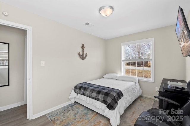 bedroom featuring visible vents, baseboards, and wood finished floors