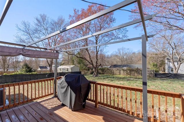 wooden terrace featuring a yard, a fenced backyard, and a grill