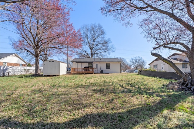 view of yard with a deck, a storage shed, fence, and an outdoor structure