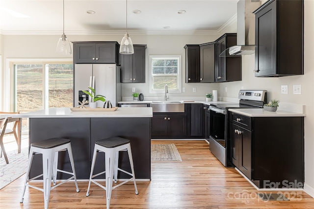 kitchen featuring stainless steel appliances, a breakfast bar, a kitchen island, a sink, and wall chimney range hood