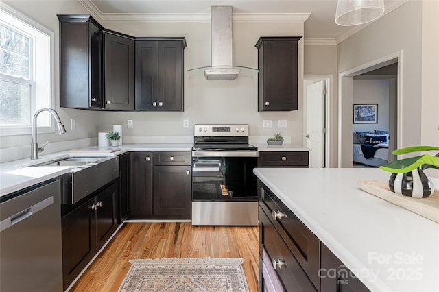 kitchen with stainless steel appliances, crown molding, light countertops, wall chimney range hood, and a sink