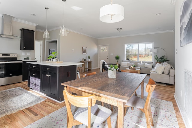 dining space featuring light wood-style flooring, baseboards, and crown molding