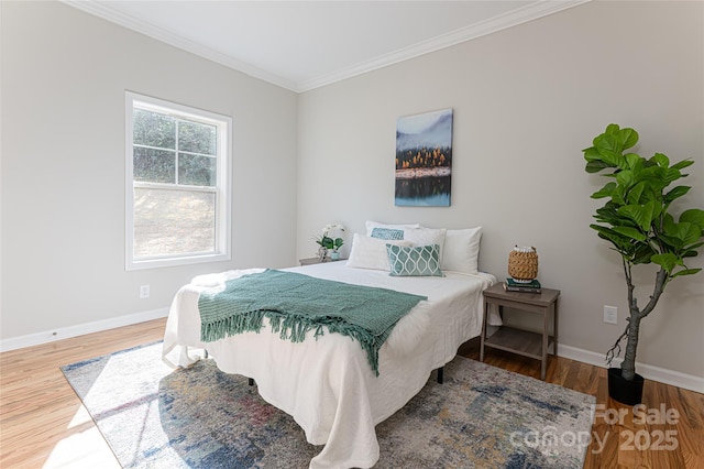 bedroom with ornamental molding, baseboards, and wood finished floors