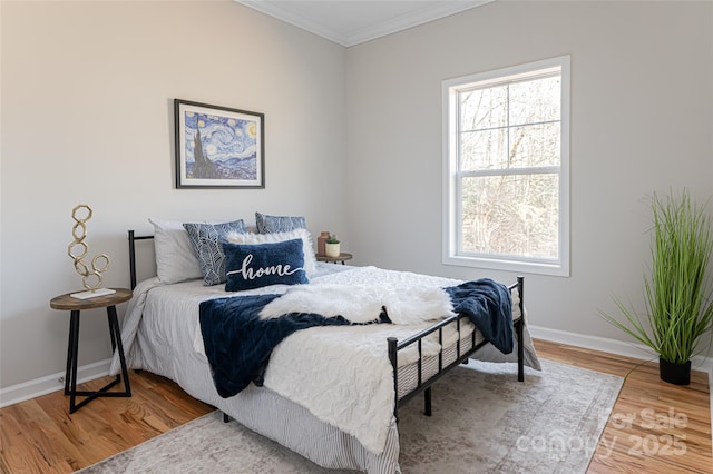 bedroom featuring baseboards, wood finished floors, and crown molding