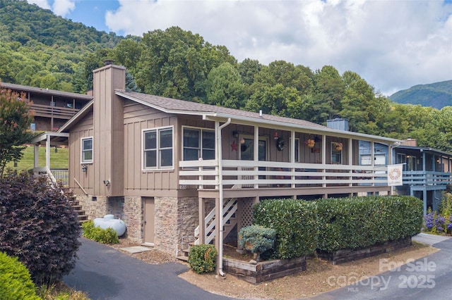 view of front of house featuring stairway, board and batten siding, a chimney, and a mountain view