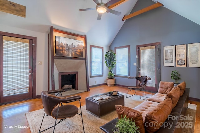 living area with a fireplace with flush hearth, high vaulted ceiling, baseboards, and wood finished floors