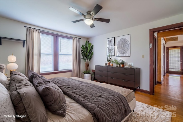 bedroom with light wood-type flooring, a ceiling fan, and baseboards