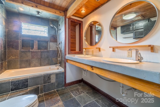 bathroom with stone tile floors, wood ceiling, a sink, tiled shower / bath combo, and baseboards