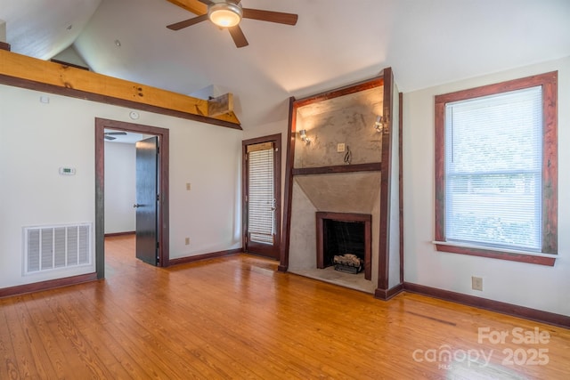 unfurnished living room with lofted ceiling, visible vents, a large fireplace, wood finished floors, and baseboards