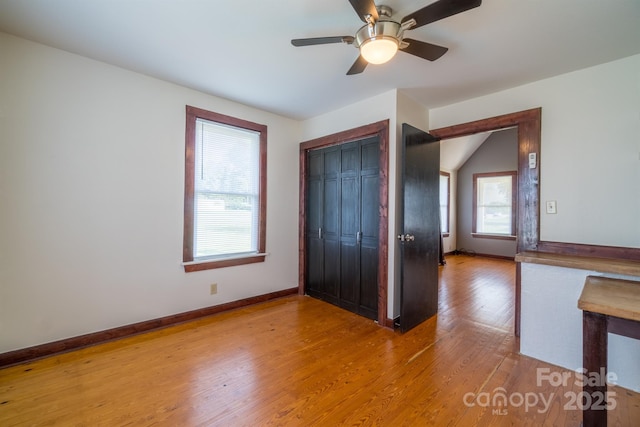 unfurnished bedroom featuring light wood-style floors, a closet, baseboards, and a ceiling fan