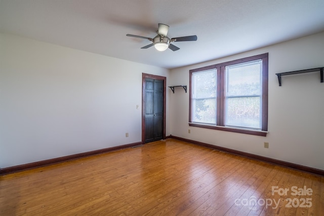 unfurnished room featuring a ceiling fan, baseboards, and hardwood / wood-style flooring