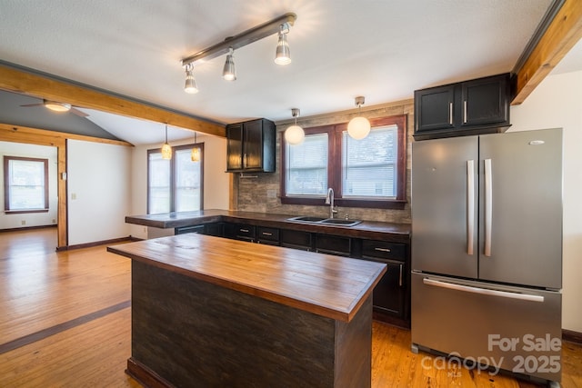 kitchen with a peninsula, wood counters, a sink, and freestanding refrigerator