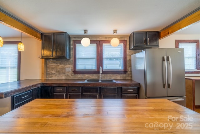 kitchen featuring butcher block counters, a sink, freestanding refrigerator, and a healthy amount of sunlight