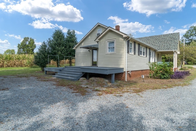 view of side of home with a shingled roof, a chimney, and a wooden deck