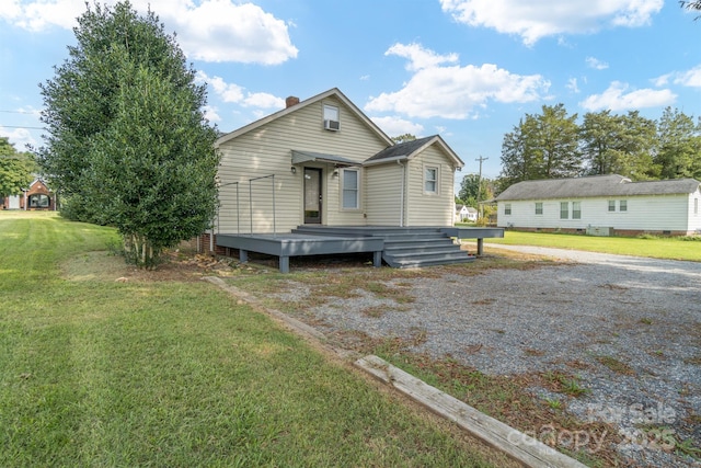 bungalow-style home with a front yard, a chimney, and a wooden deck