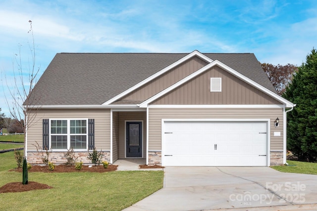 view of front of house featuring roof with shingles, concrete driveway, a front yard, a garage, and stone siding