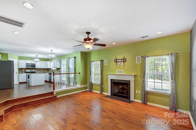 unfurnished living room featuring a fireplace with flush hearth, recessed lighting, visible vents, and wood finished floors