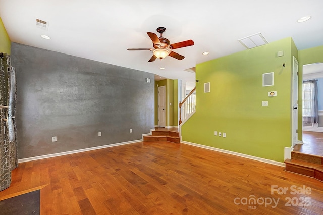 unfurnished room featuring baseboards, stairs, visible vents, and wood finished floors