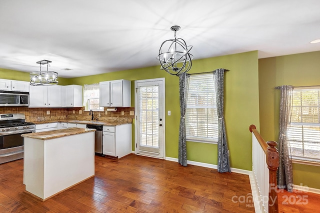 kitchen featuring stainless steel appliances, a sink, white cabinets, tasteful backsplash, and dark wood finished floors