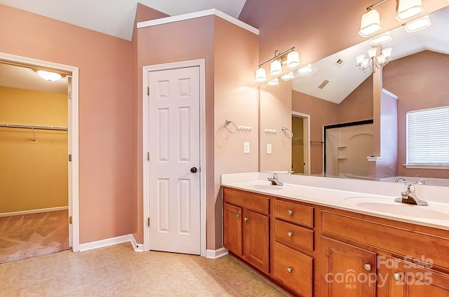 full bath with vaulted ceiling, a sink, baseboards, and double vanity