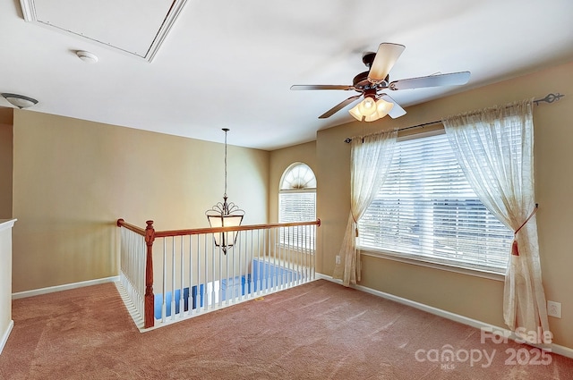 spare room with attic access, carpet floors, baseboards, and a ceiling fan