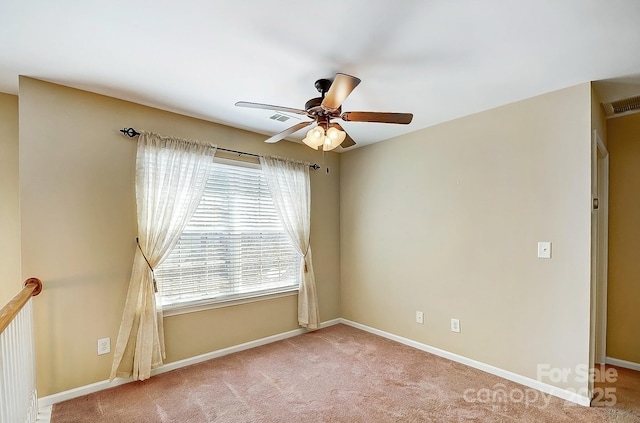 carpeted spare room with visible vents, ceiling fan, and baseboards