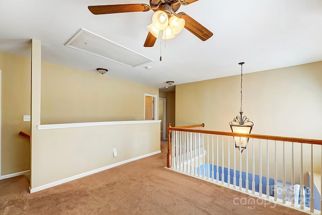 spare room featuring carpet, attic access, and baseboards