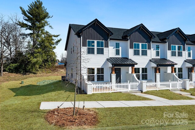 view of front of house with metal roof, a fenced front yard, board and batten siding, a front lawn, and a standing seam roof