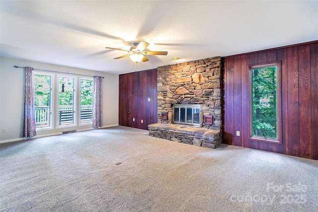 162 Southerland Rd, Pisgah Forest, NC 28768 - unfurnished living room featuring healthy amount of natural light, ceiling fan, carpet floors, a stone fireplace, and wood walls