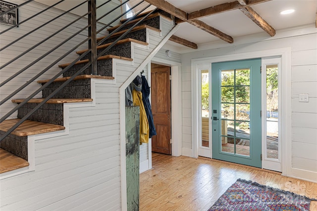 entryway with hardwood / wood-style floors, beam ceiling, wooden walls, and stairway