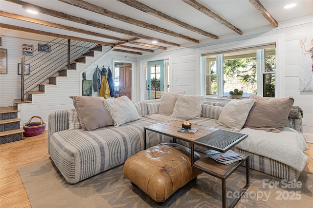 living area featuring beam ceiling, stairway, wooden walls, and wood finished floors