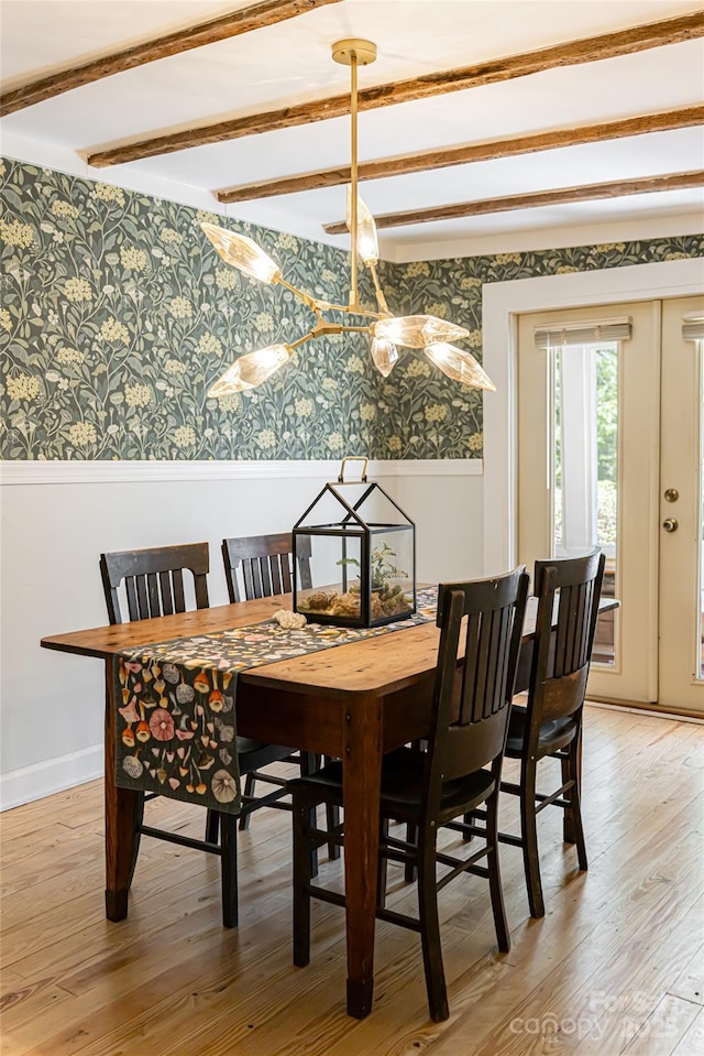 dining space featuring beamed ceiling, wallpapered walls, light wood-type flooring, and baseboards