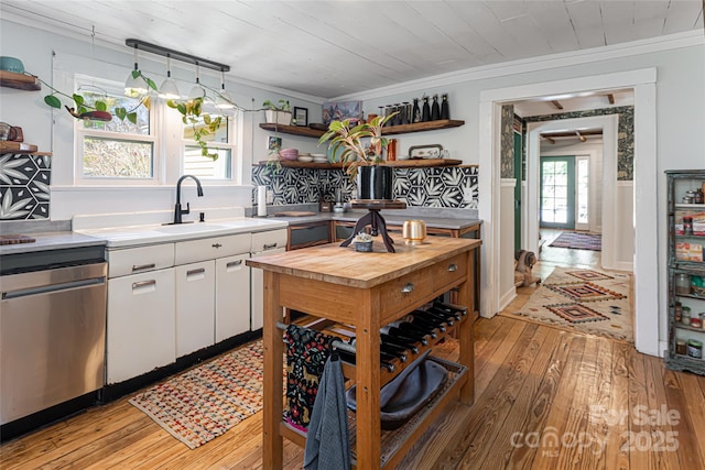 kitchen featuring open shelves, a sink, stainless steel dishwasher, white cabinetry, and crown molding